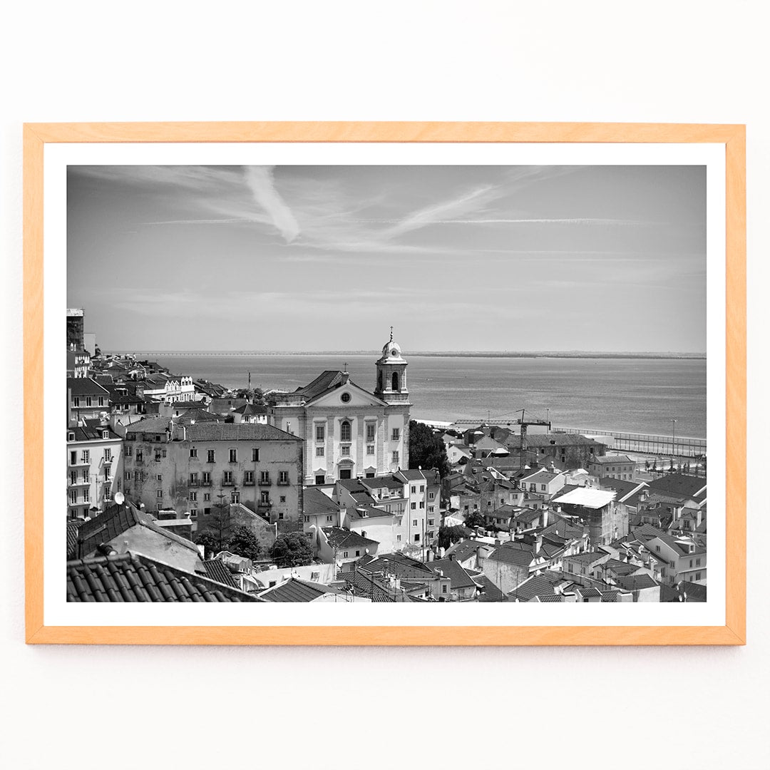Black and white landscape poster of Alfama Lisbon Old City with traditional buildings and Tagus River by artist Alfama Lisbon, framed and displayed in modern living room decor