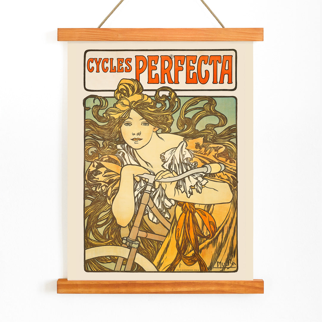Art Nouveau poster of a woman with flowing hair riding a bicycle with decorative floral design by Alphonse Mucha for Cycles Perfecta, with wooden magnetic frame on white background