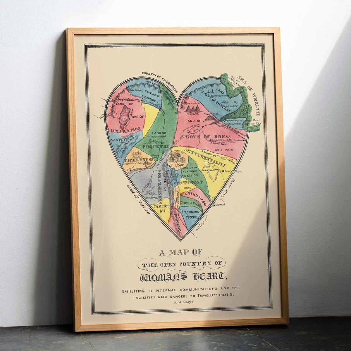 Open Country of Womans Heart poster by E.B. and E.C. Kellogg, colorful heart shaped map with labeled regions, vintage cartographic style, with wooden magnetic frame on white background