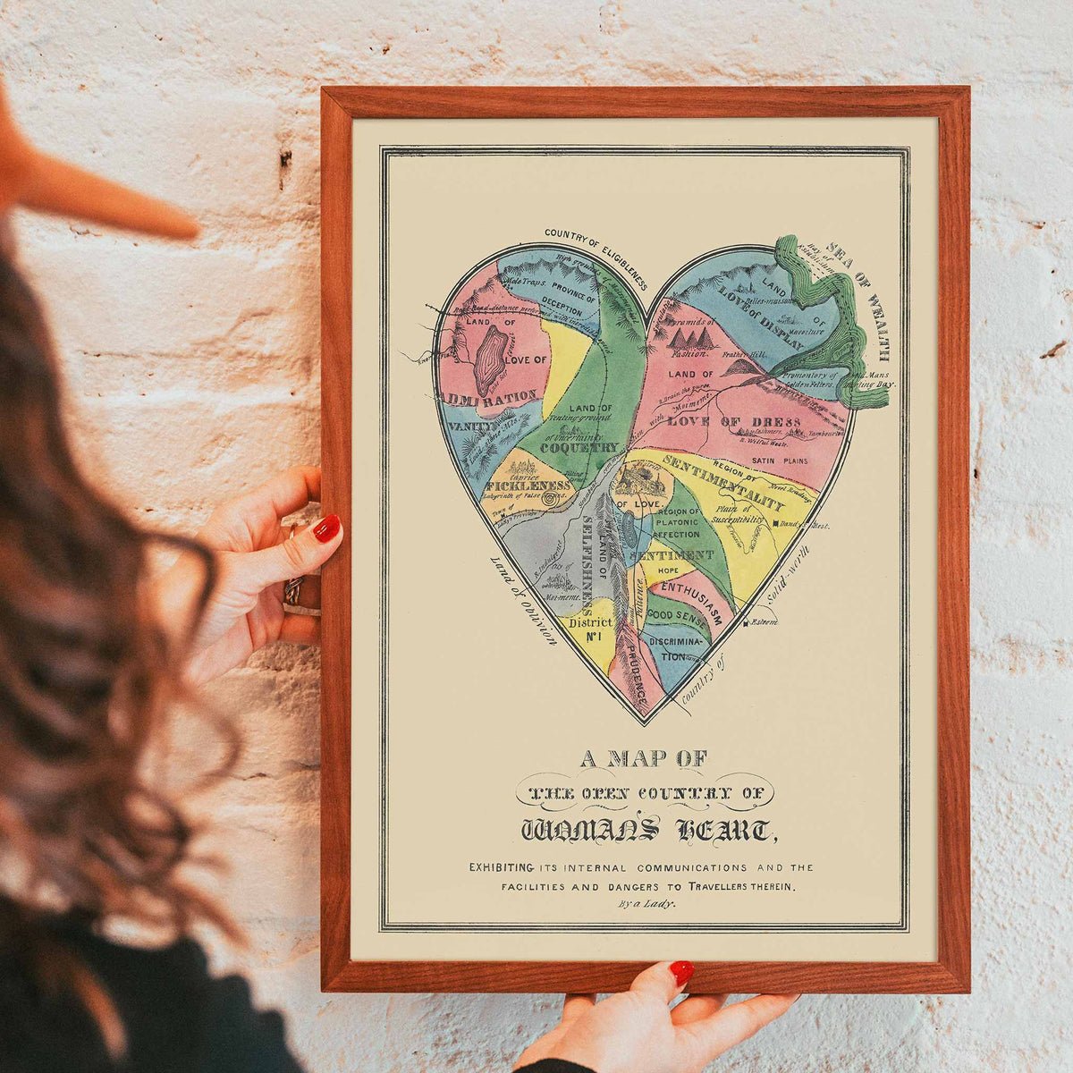 Open Country of Womans Heart poster by E.B. and E.C. Kellogg, colorful heart shaped map with labeled regions, vintage cartographic style, framed and displayed in modern living room decor