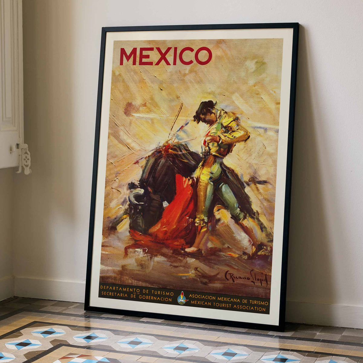 Mexico travel poster by Carlos Ruano Llopis showing a matador facing a bull in a dramatic vintage tourism scene, framed and displayed in modern living room decor