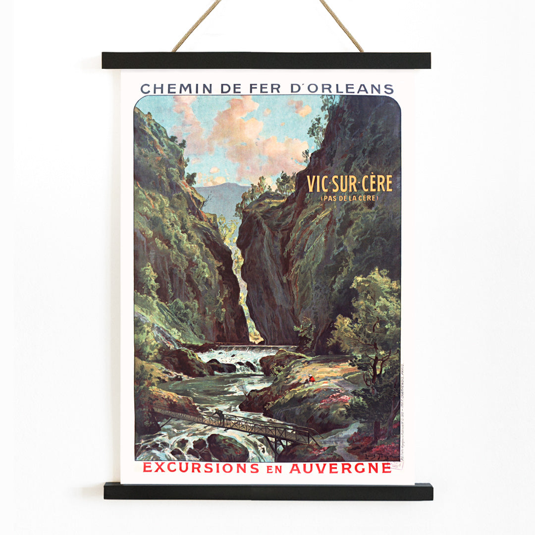 Scenic mountain gorge with river and footbridge in Vic Sur Cere travel poster by Louis Tauzin artwork for excursions in Auvergne, with wooden magnetic frame on white background