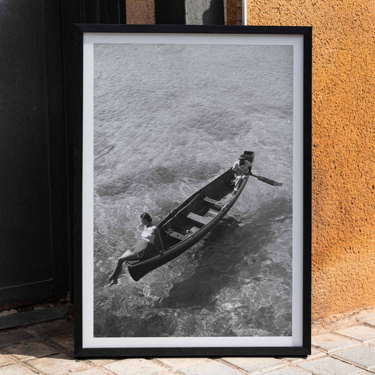 Fashion model on boat edge with man rowing in clear water Montego Bay Jamaica by Toni Frissell artwork poster, framed and displayed in home decor