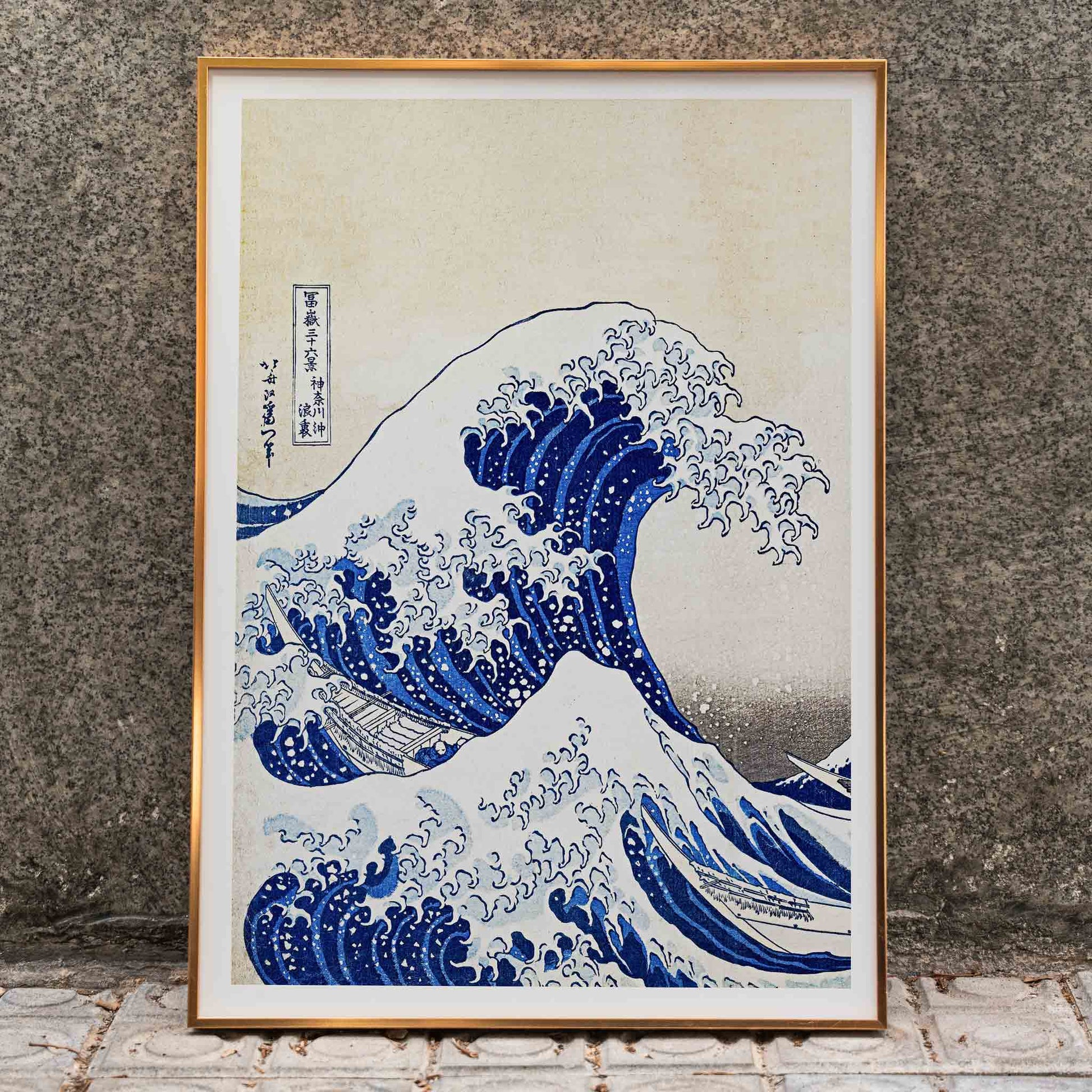 The Great Wave off Kanagawa by Katsushika Hokusai showing a dramatic large wave threatening small boats with Mount Fuji in the background, framed and displayed in home decor