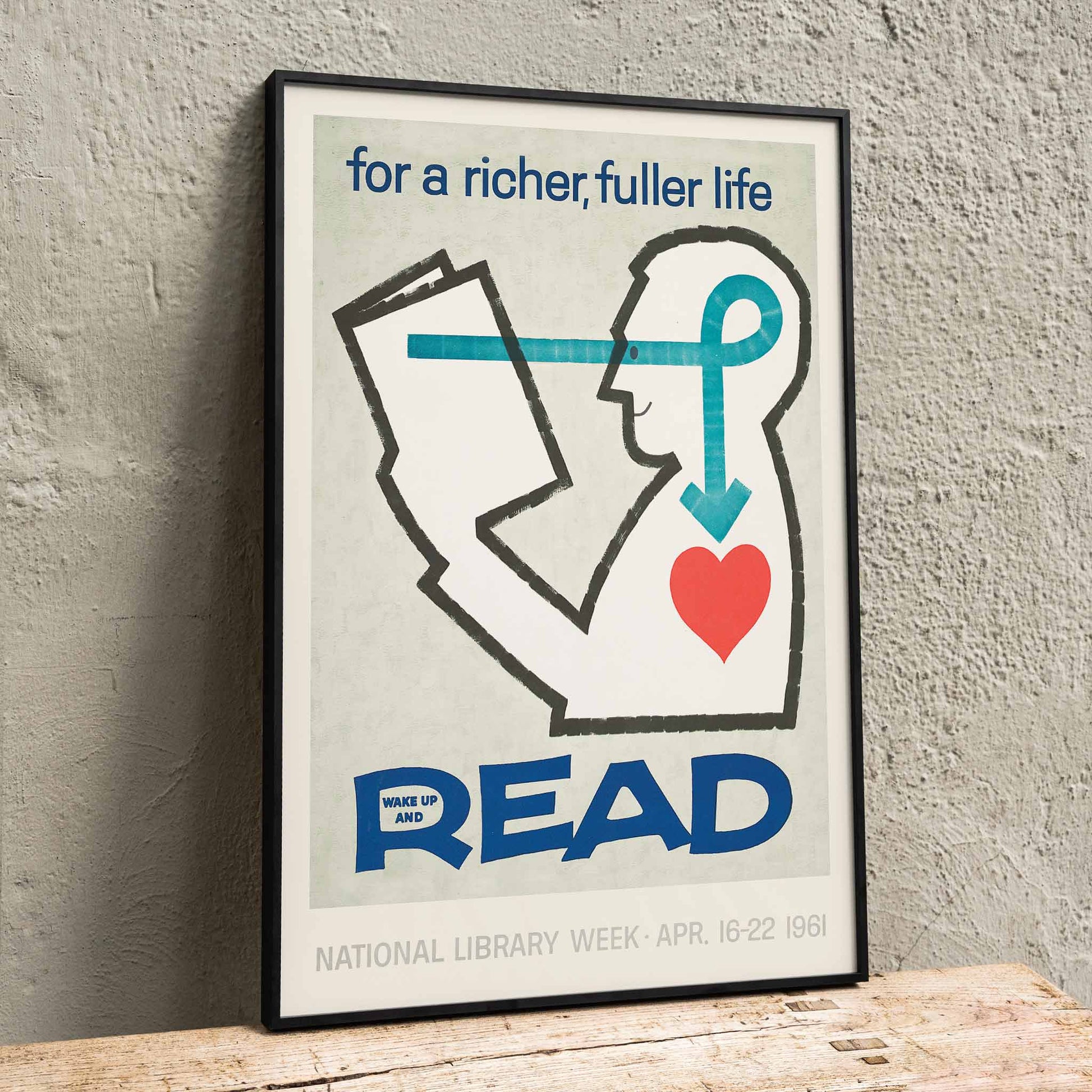 Poster with a stylized person reading a book and heart with bold text for a richer fuller life wake up and read by National Library, framed and displayed in home decor